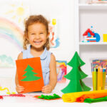 Laughing,Girl,Holding,Carton,Card,With,Xmas,Tree